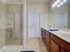 Bright bathroom showcases a glass shower, a double sink vanity with wood cabinets and tiled floors at 19240 Isadora St, Venice, FL 34293