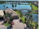 Beautiful lakefront property with a bridge, lush landscaping, and a paver driveway at 19240 Isadora St, Venice, FL 34293