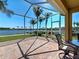 Screened-in patio with brick flooring and a beautiful lake view with palm trees at 19240 Isadora St, Venice, FL 34293