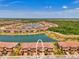 Aerial view of townhomes next to a large lake, surrounded by a lush landscape at 20390 Lagente Cir, Venice, FL 34293