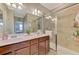 Bathroom featuring double sinks, granite counters, glass shower doors and views to an adjacent bedroom at 20390 Lagente Cir, Venice, FL 34293