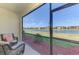 A screened lanai overlooks a tranquil lake view with inviting wicker furniture for outdoor relaxation at 20390 Lagente Cir, Venice, FL 34293