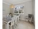 Dining room showcases elegant white table setting, natural light, and view to the screened pool and backyard area at 20591 Ovid Ln, Venice, FL 34293