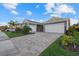 Beautiful home featuring a brick driveway, two-car garage, lush landscaping, and cozy porch at 20591 Ovid Ln, Venice, FL 34293