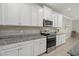 Clean kitchen with granite counters, white cabinets, and stainless steel microwave and oven at 20591 Ovid Ln, Venice, FL 34293
