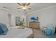 Comfortable main bedroom features a ceiling fan, natural light, a wood dresser with TV, and a chair with blue accents at 20591 Ovid Ln, Venice, FL 34293