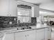 Modern kitchen boasts a stainless steel sink, gray-tone backsplash, white cabinets, and marble countertops at 2108 Lee Ln, Sarasota, FL 34231