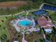 Aerial view of a community pool, spa, and tennis courts surrounded by palm trees at 220 Sarezzo Cir, Nokomis, FL 34275