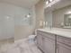 A well-lit bathroom featuring double sinks, granite countertops, mirrors and a spacious walk-in shower at 220 Sarezzo Cir, Nokomis, FL 34275