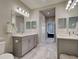 Bathroom featuring gray vanity cabinets, marble countertops, large mirrors, vanity lights and separate toilet at 220 Sarezzo Cir, Nokomis, FL 34275