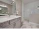 Bathroom featuring gray vanity cabinets, marble countertops, large mirror and glass-enclosed walk-in shower with tile at 220 Sarezzo Cir, Nokomis, FL 34275