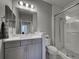 Bathroom featuring gray vanity cabinet, marble countertops, vanity lights, and a walk-in shower with glass door at 220 Sarezzo Cir, Nokomis, FL 34275