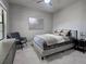 Stylish bedroom features a ceiling fan, soft carpet, accent wall art, a gray bed and a comfy chair at 220 Sarezzo Cir, Nokomis, FL 34275