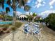 Outdoor lounge area with tables and chairs surrounded by lush landscaping near the pool at 220 Sarezzo Cir, Nokomis, FL 34275