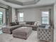 Living room with a large sectional sofa, ottoman, and tufted chair at 220 Sarezzo Cir, Nokomis, FL 34275