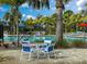 Community pool with blue umbrellas and lawn chairs in a tropical landscaped setting with palm trees at 220 Sarezzo Cir, Nokomis, FL 34275