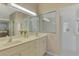 Well-lit bathroom featuring dual sinks and a glass-enclosed shower for a spa-like experience at 2318 Harrier Way, Nokomis, FL 34275