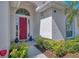 Close up on a red front door, showing the landscaping and architectural detail at 2318 Harrier Way, Nokomis, FL 34275