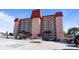 Spacious condo building with a light exterior, parking, and palm trees against a blue sky at 244 Saint Augustine # 605, Venice, FL 34285