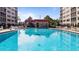 Exterior shot of community pool with lounge chairs, building and lush trees at 244 Saint Augustine # 605, Venice, FL 34285