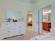 Bedroom with white dresser leading to a bathroom and another room with brown chaise lounge at 275 Capulet Dr, Venice, FL 34292