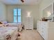 Bedroom with two twin beds, shuttered window, white dresser with mirror, and beige carpet at 275 Capulet Dr, Venice, FL 34292