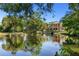 Stunning view of estate home overlooking a serene pond surrounded by mature trees on a sunny day at 2750 Gocio Road Ext, Sarasota, FL 34235