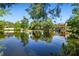 Scenic view of the expansive pond reflecting the surrounding trees and estate home at 2750 Gocio Road Ext, Sarasota, FL 34235