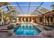Inviting screened-in pool area with outdoor kitchen, lounging area, fireplace, and well-manicured landscaping at 2750 Gocio Road Ext, Sarasota, FL 34235