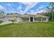 Inviting single-story home featuring a lush green lawn, red shutters, and mature landscaping at 2834 Coolidge Ave, North Port, FL 34286