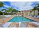 Community pool with palm trees and white lounge chairs on the brick patio at 301 Ravinia Cir # 301B2, Venice, FL 34292