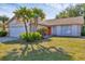 Charming single-story home featuring a well-manicured lawn and tropical landscaping at 3181 E Village Dr, Venice, FL 34293