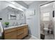Bright bathroom featuring a wood vanity, updated mirror, toilet and an adjoining shower area at 3355 Roslyn Rd, Venice, FL 34293