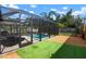 Screened in pool with artificial turf, gravel area, and lush green landscaping at 348 Dorchester Dr, Venice, FL 34293