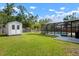 Spacious backyard with a storage shed, green grass, landscaping, and screened pool at 348 Dorchester Dr, Venice, FL 34293