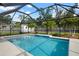 Screened pool with blue tile accents and white trim and a view of fenced yard with palm trees at 348 Dorchester Dr, Venice, FL 34293