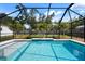 Large swimming pool enclosed with a screen, surrounded by palm trees and backyard at 348 Dorchester Dr, Venice, FL 34293