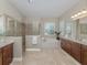 Bright bathroom featuring double vanity, tub, and glass-enclosed shower in a home at 353 Marsh Creek Rd, Venice, FL 34292