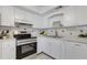 Updated kitchen boasts white cabinets, stainless steel appliances, and a functional layout at 360 Base E Ave # 413, Venice, FL 34285