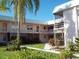 Two-story condo building featuring white exterior, balconies, green lawn, and mature trees, offering a serene living environment at 400 Base # 225, Venice, FL 34293