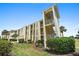 Low-angle exterior view of a condo with green grass and surrounding shrubs at 406 Cerromar N Cir # 128, Venice, FL 34293