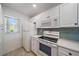 Cozy kitchen with white cabinets, appliances, and a sunny window at 406 Cerromar N Cir # 128, Venice, FL 34293