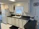 A clean kitchen featuring white appliances and cabinets with black countertops and tiled backsplash at 411 Cervina N Dr # 493, Venice, FL 34285