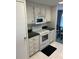 A view of the kitchen with white cabinets and appliances, including a microwave and stove, and tiled floor at 411 Cervina N Dr # 493, Venice, FL 34285