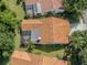 Aerial view of a home with an orange tile roof and a screened-in patio, surrounded by lush landscaping at 4885 Tamarack Trl, Venice, FL 34293