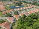 Aerial view of a neighborhood with multiple homes and a scenic pond, surrounded by lush trees at 4885 Tamarack Trl, Venice, FL 34293