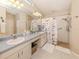 Bright bathroom featuring double sinks, a large mirror, and a tiled walk-in shower at 4885 Tamarack Trl, Venice, FL 34293
