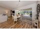 Bright dining area with wood floors, leading to a screened patio with outdoor seating and views of the lush backyard at 4885 Tamarack Trl, Venice, FL 34293