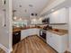 Well-lit kitchen boasts white cabinets, stainless steel appliances, granite countertops, and wood flooring at 4885 Tamarack Trl, Venice, FL 34293