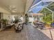 Covered brick patio with a seating area and an enclosed patio with a dining table and a swing at 4885 Tamarack Trl, Venice, FL 34293